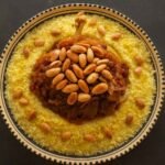 Moroccan Riviera Menu Marrakech: Chicken couscous with tfaya (caramelized onions and raisins) topped with toasted almonds on a Moroccan ceramic plate